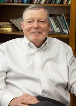 Pastor Dr. Doug Parsons headshot in his office with books on a bookshelf behind him